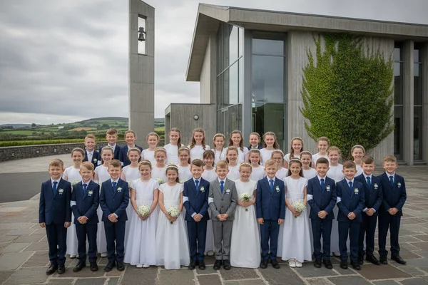 First Holy Communion Boys and Girls group posing outside the church.